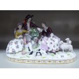 A mid 20thC Continental porcelain group, three seated figures beside lambs, on a plinth 6.