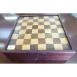 An early 20thC mahogany games box, the hinged lid with an inlaid chessboard,