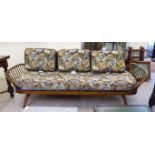 An Ercol stained beech and elm framed three person bed settee with a lozenge shaped, panelled back,