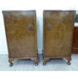 A pair of 1930s walnut veneered bedside cupboards, each enclosed by a full-height door,