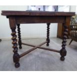 A 1920s oak draw leaf dining table with a panelled top, raised on barleytwist legs,