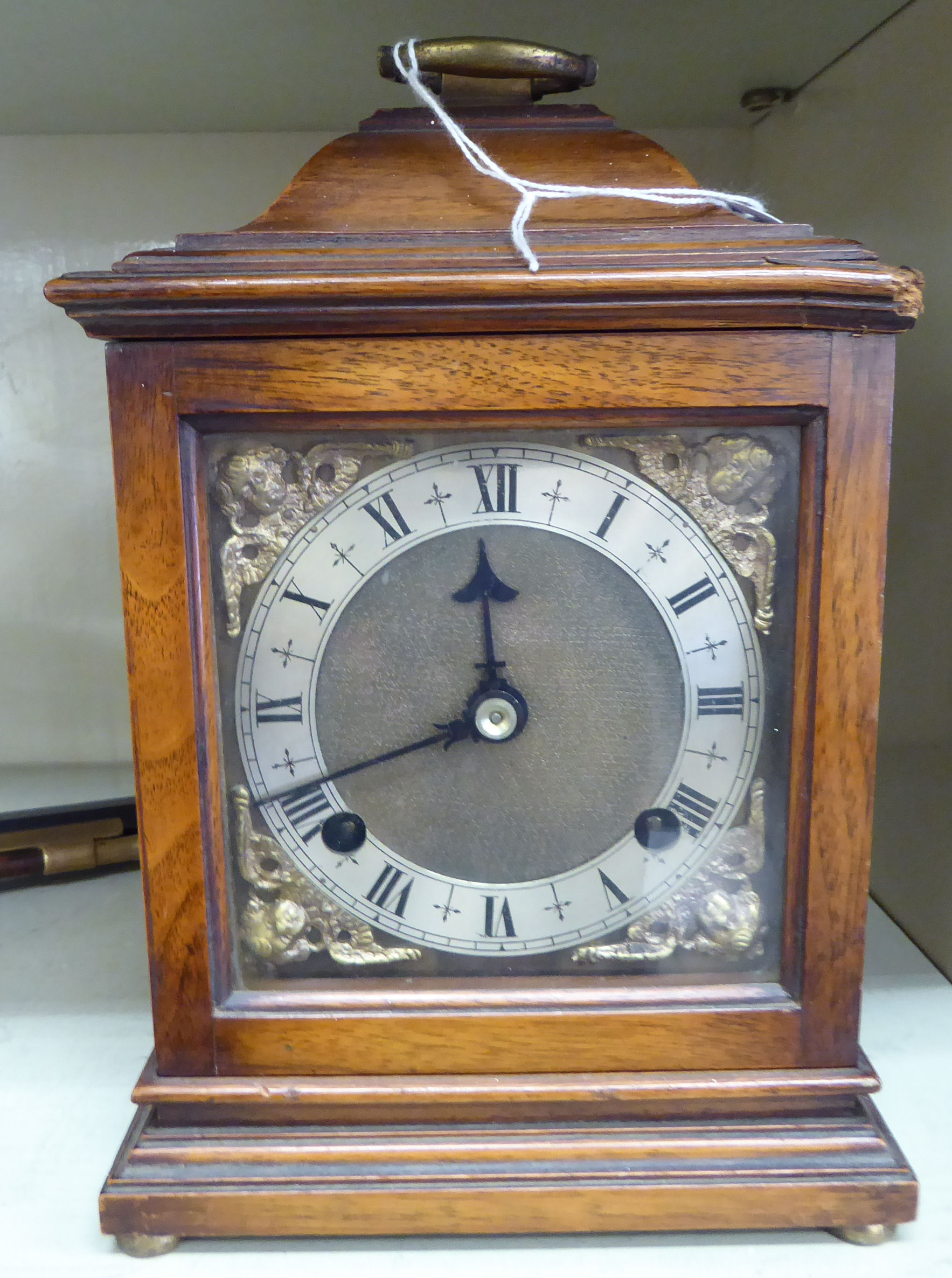 A Georgian style mahogany cased bracket clock, having a folding brass handle on the domed top,