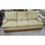 A modern three person settee, upholstered in biscuit coloured fabric with cushioned back and seats,