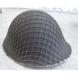 A British steel military helmet with a cloth webbed camouflage cover (Please Note: this lot is