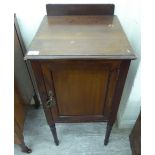 An Edwardian mahogany pot cupboard, enclosed by a panelled door,