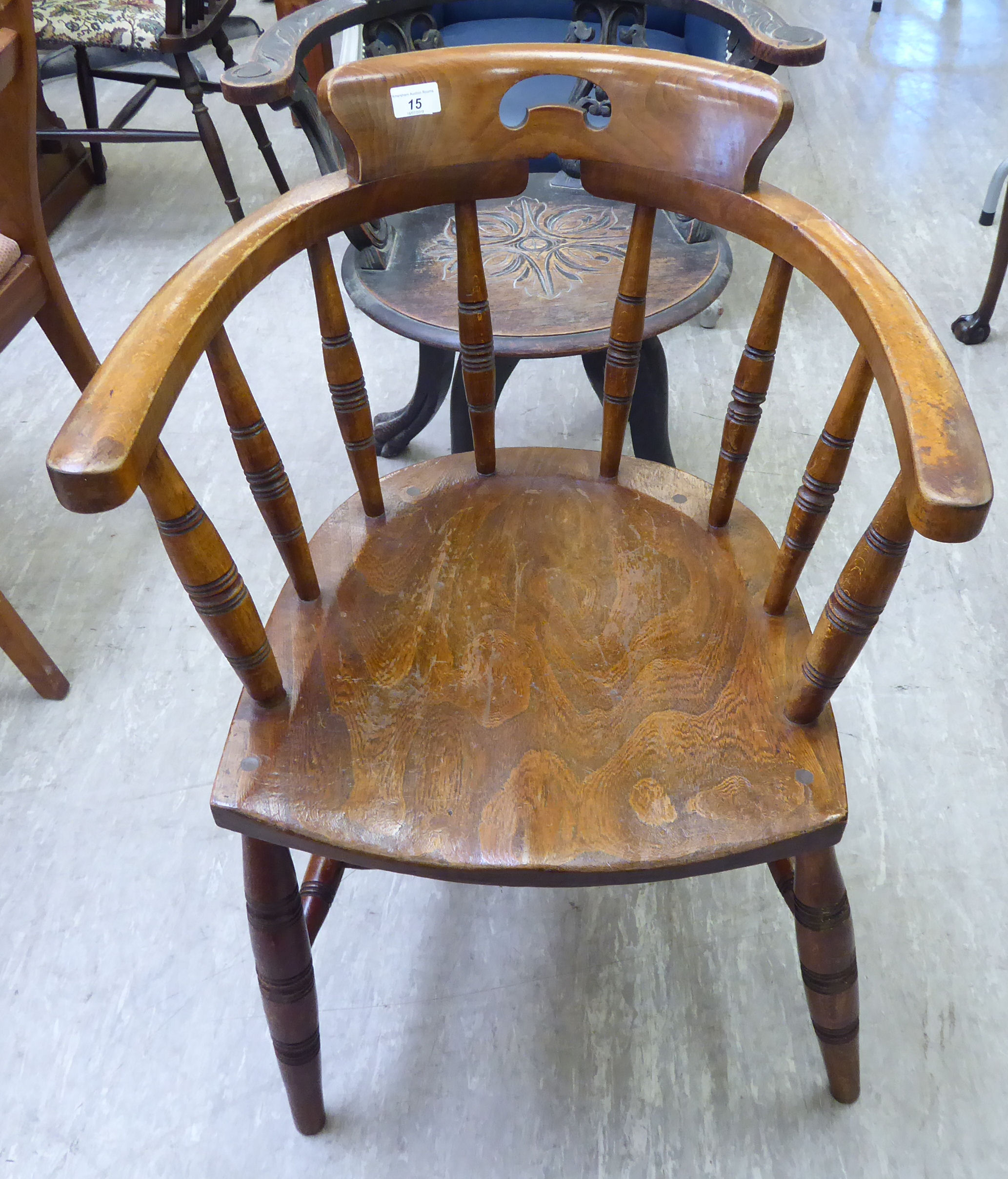 An early 20thC beech and elm framed captain's chair with a spindled back,