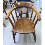 An early 20thC beech and elm framed captain's chair with a spindled back,