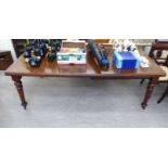 A mid Victorian mahogany dining table, the top with rounded corners, raised on turned, tapered,