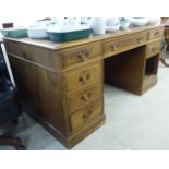 A mid 20thC oak desk, the top having a tooled hide scriber, over three frieze drawers,