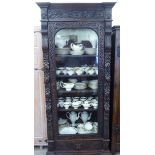 A late Victorian dark stained and carved oak display cabinet/bookcase, the full height, arched,