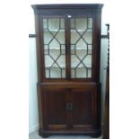 A George III oak corner cabinet with two astragal glazed doors and two panelled doors,
