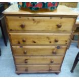 A modern honey coloured pine five drawer dressing chest,