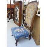 A late Victorian walnut framed nursing chair with a tapestry upholstered back and seat,