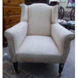 An Edwardian mahogany framed wingback armchair, later upholstered in an oatmeal coloured fabric,