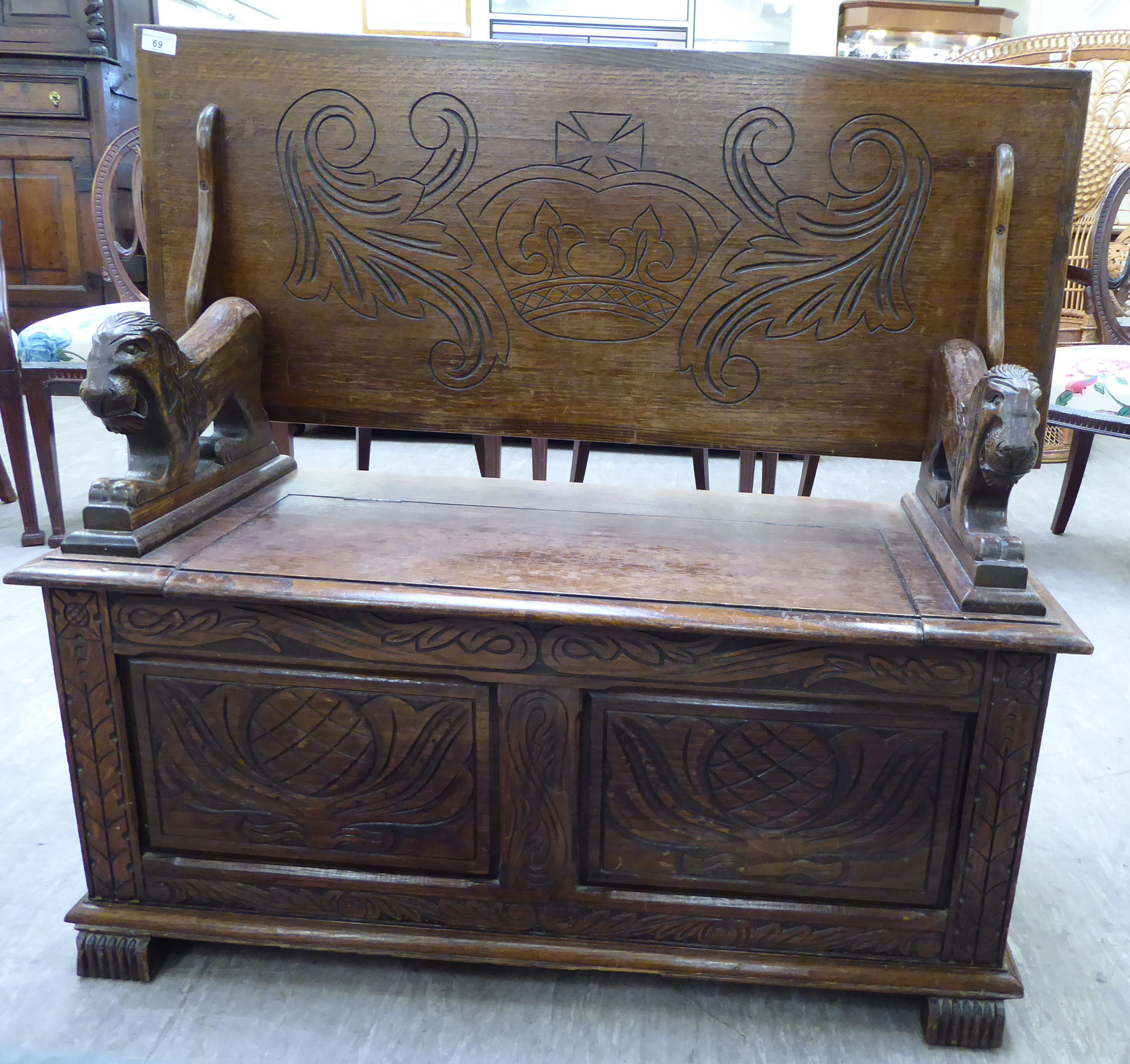 A 1920s/30s oak monk's bench with lion carved arms and a hinged seat,