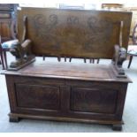 A 1920s/30s oak monk's bench with lion carved arms and a hinged seat,