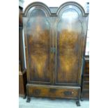 A mid 20thC Queen Anne design, double domed top, walnut wardrobe with two doors and a base drawer,