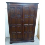 A 1920s 19thC style oak wardrobe, enclosed by a pair of multi-fielded panelled,