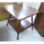 A 1930s oak two tier occasional table, raised on turned,