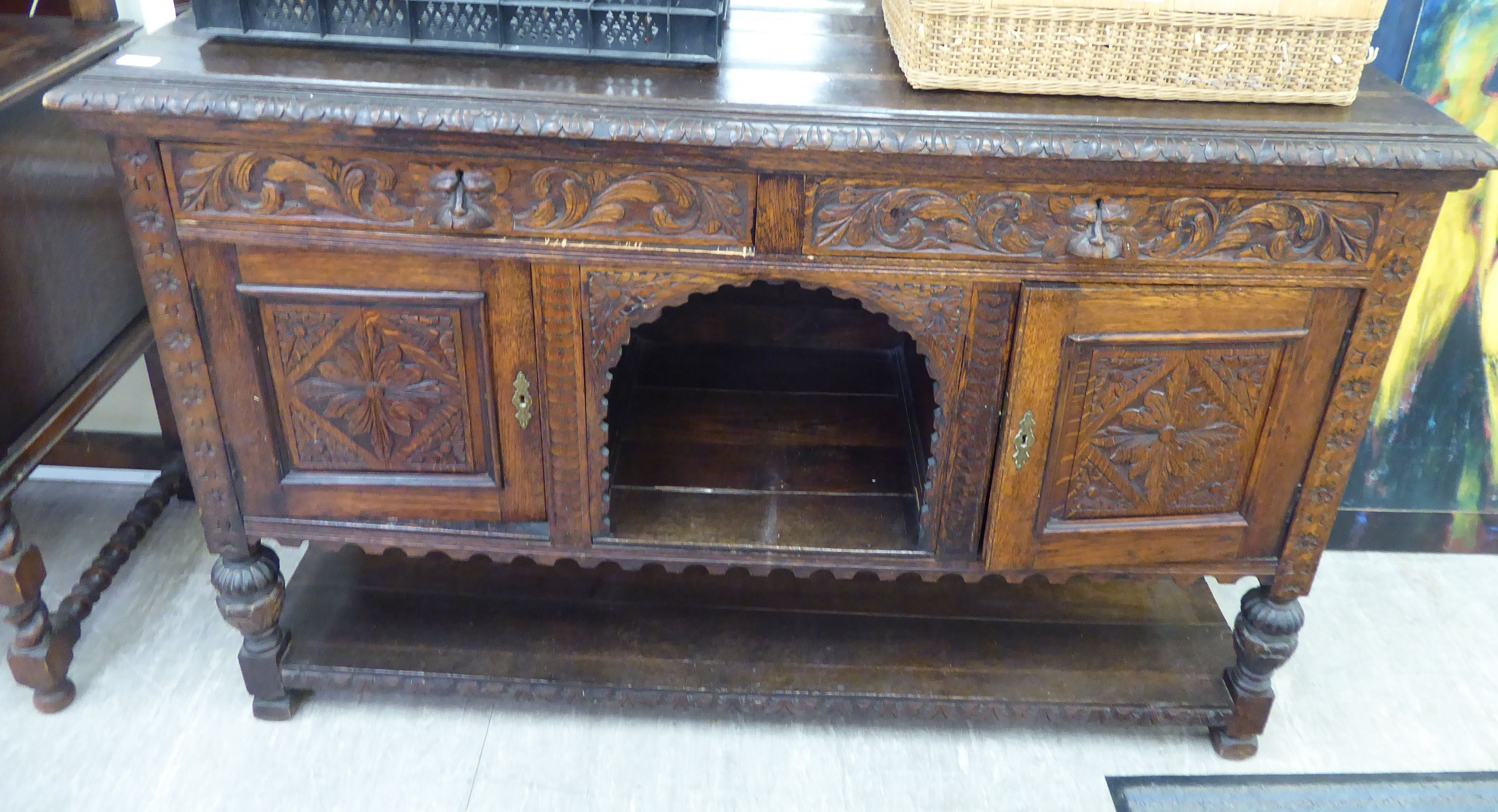 A late Victorian profusely carved oak sideboard, comprising an arrangement of cupboards and doors,