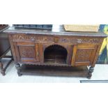 A late Victorian profusely carved oak sideboard, comprising an arrangement of cupboards and doors,