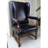 A modern stained beech framed wingback library chair, upholstered in black hide, raised on turned,