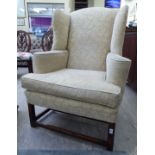 A late 19thC mahogany wingback armchair, later upholstered in an oatmeal coloured fabric,