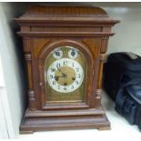 An early 20thC carved oak cased mantel clock with a domed platform top, over straight sides,