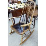 A modern stained beech framed wheelback rocking chair with a solid seat,