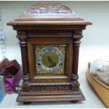 An early 20thC carved walnut cased mantel clock with a domed platform top, over straight sides,