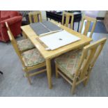 A modern polished beech extending dining table, incorporating a pair of folding leaves,