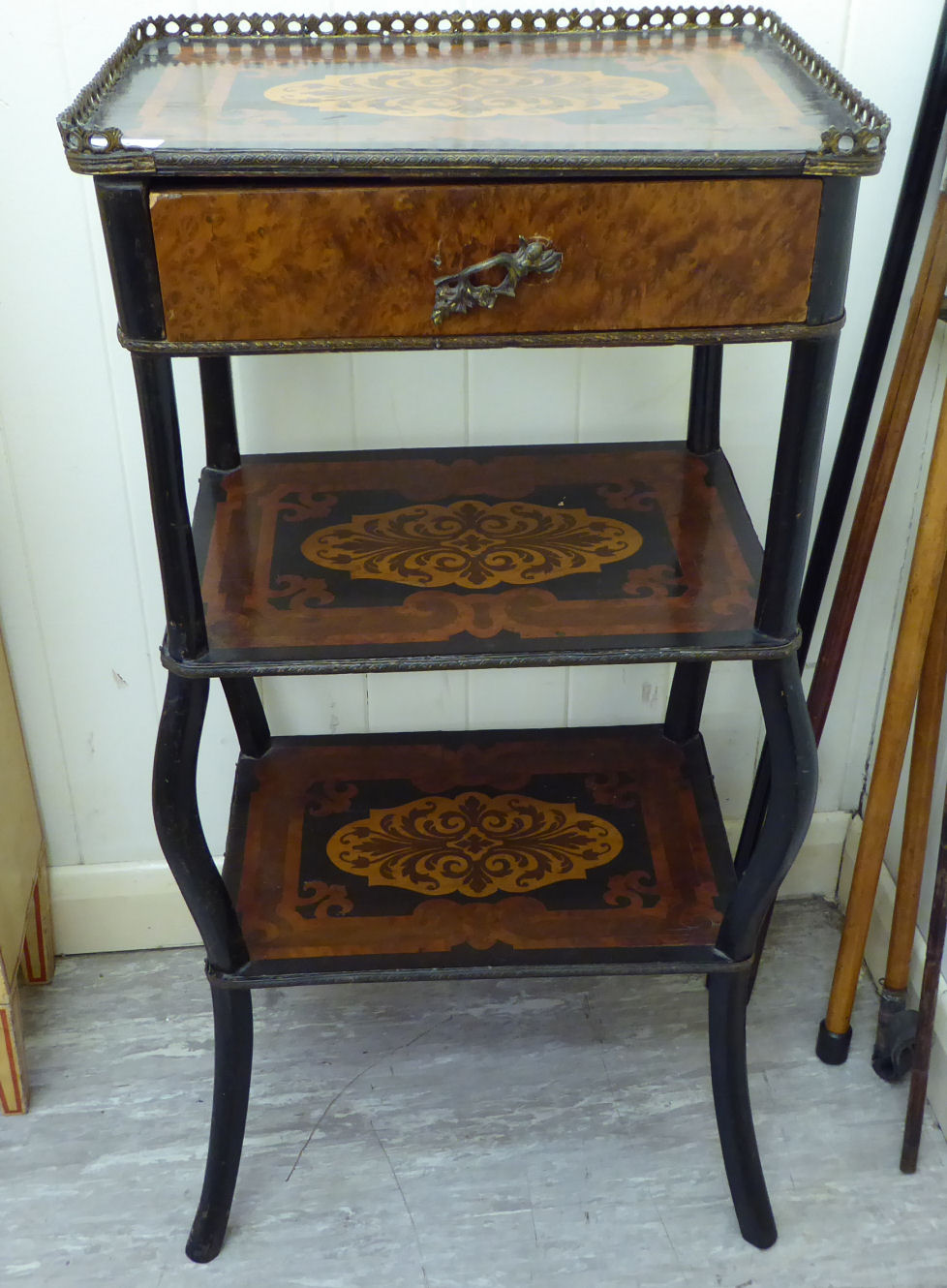 A late 19thC French walnut and marquetry inlaid three tier etagere, the top with a brass gallery,