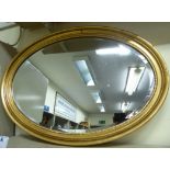 An early 20thC bevelled oval mirror,