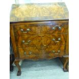 A 20thC burr walnut and mahogany finished bureau, the fall flap enclosing a part-fitted interior,