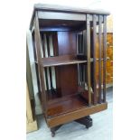 An early 20thC string inlaid mahogany rotating two tier bookcase,