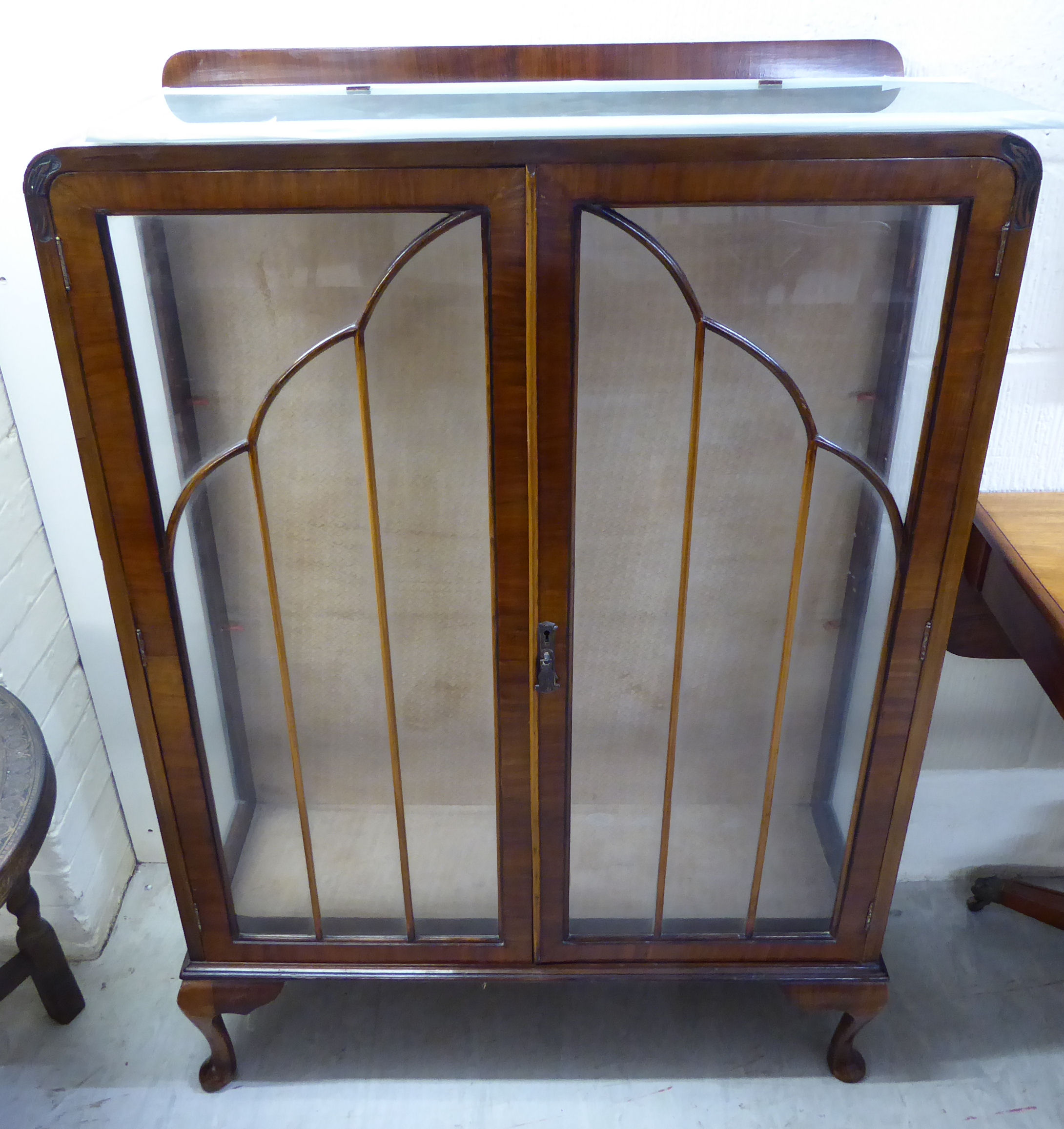 A 1930s walnut display cabinet with two astragal glazed doors, enclosing a shelved interior,