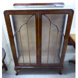 A 1930s walnut display cabinet with two astragal glazed doors, enclosing a shelved interior,