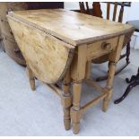 An early 20thC rustically constructed pine drop leaf kitchen table,