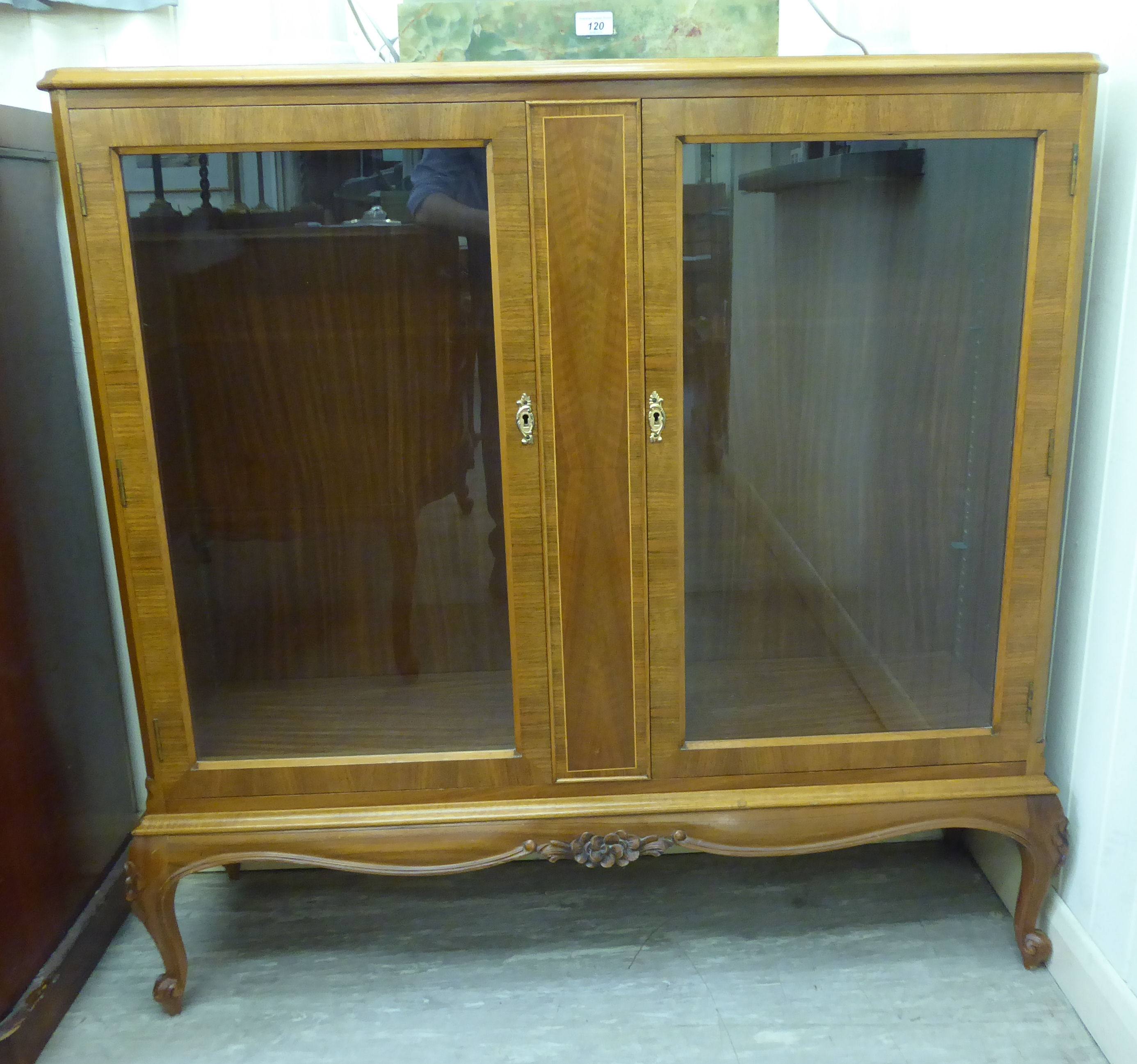 A mid 20thC walnut veneered display cabinet with two glazed doors,