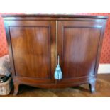 A Regency mahogany bow front cabinet, comprising two drawers, enclosing a sliding shelved interior,