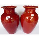 A pair of early 20thC Burmantofts red glazed faience vases of baluster form with flared filled lips,