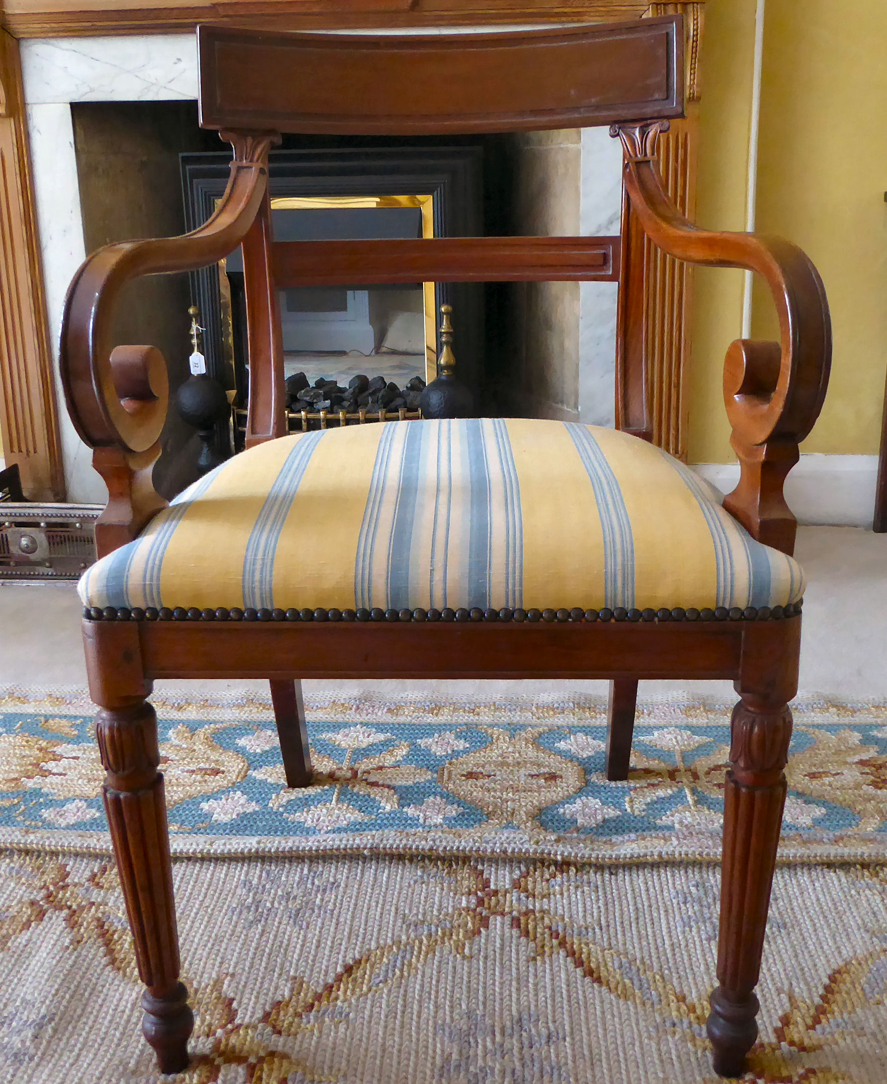 An early 20thC Regency design mahogany framed elbow chair with a stripe upholstered seat,