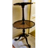 A 1920s mahogany two tier dumb waiter with lobed borders, raised on a tripod base,