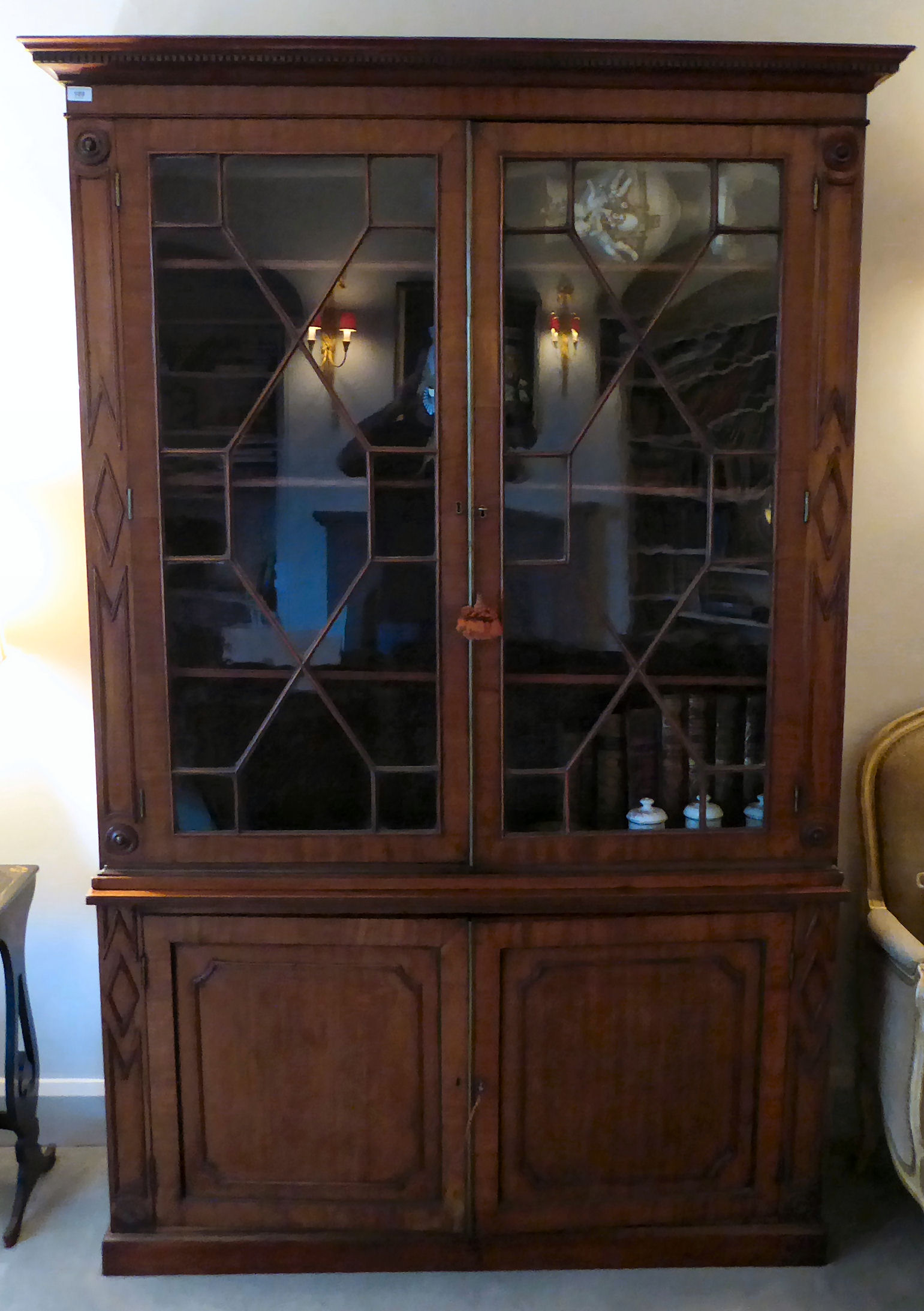 A Regency mahogany cabinet bookcase with a dentil moulded frieze,