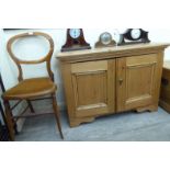 An early 20thC waxed pine cupboard, enclosed by a pair of panelled doors,