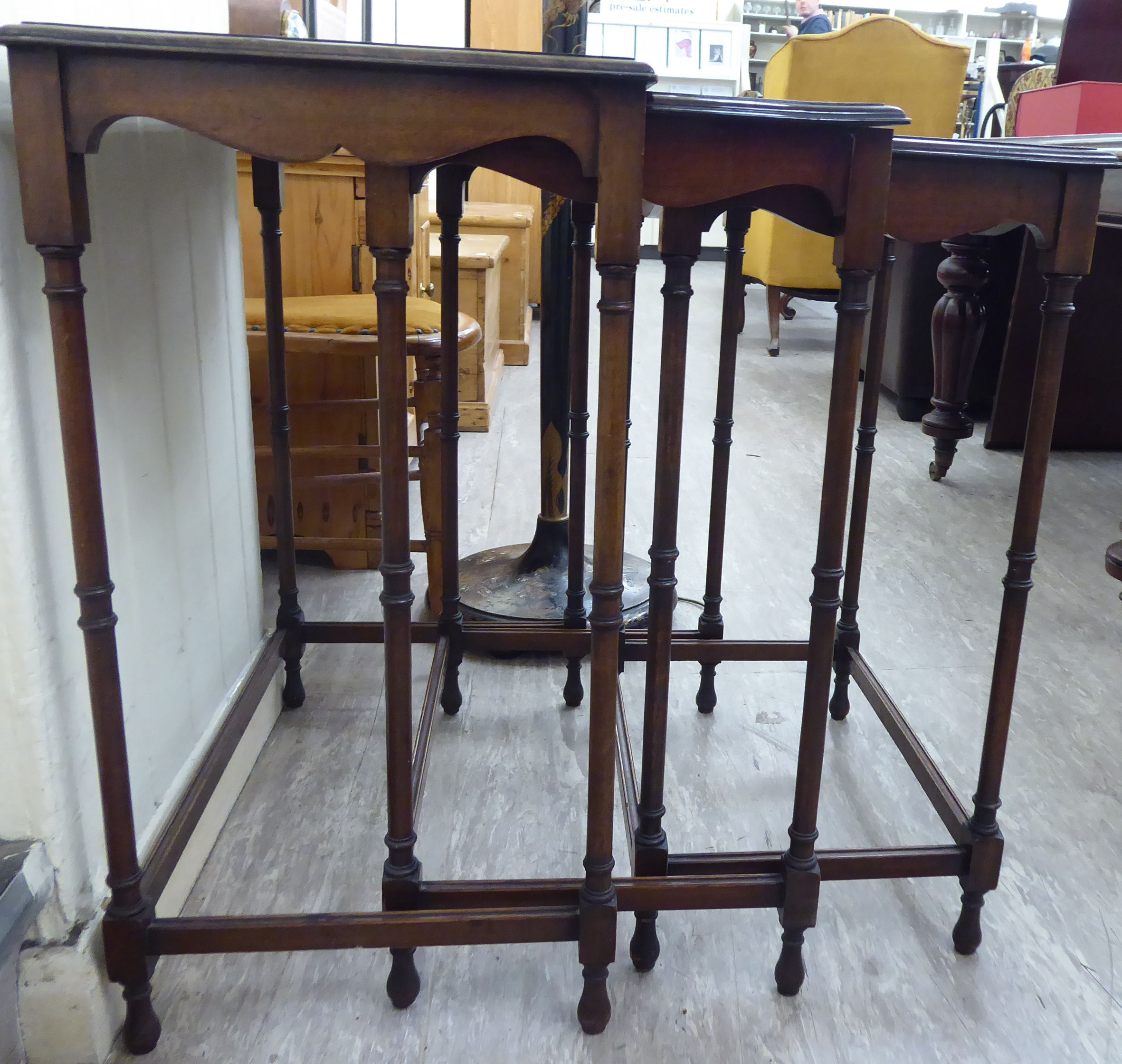 A nesting set of three 20thC mahogany occasional tables, the top with a curved edge,