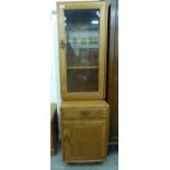 An Ercol honey coloured elm two part cupboard, comprising a shelved display section,