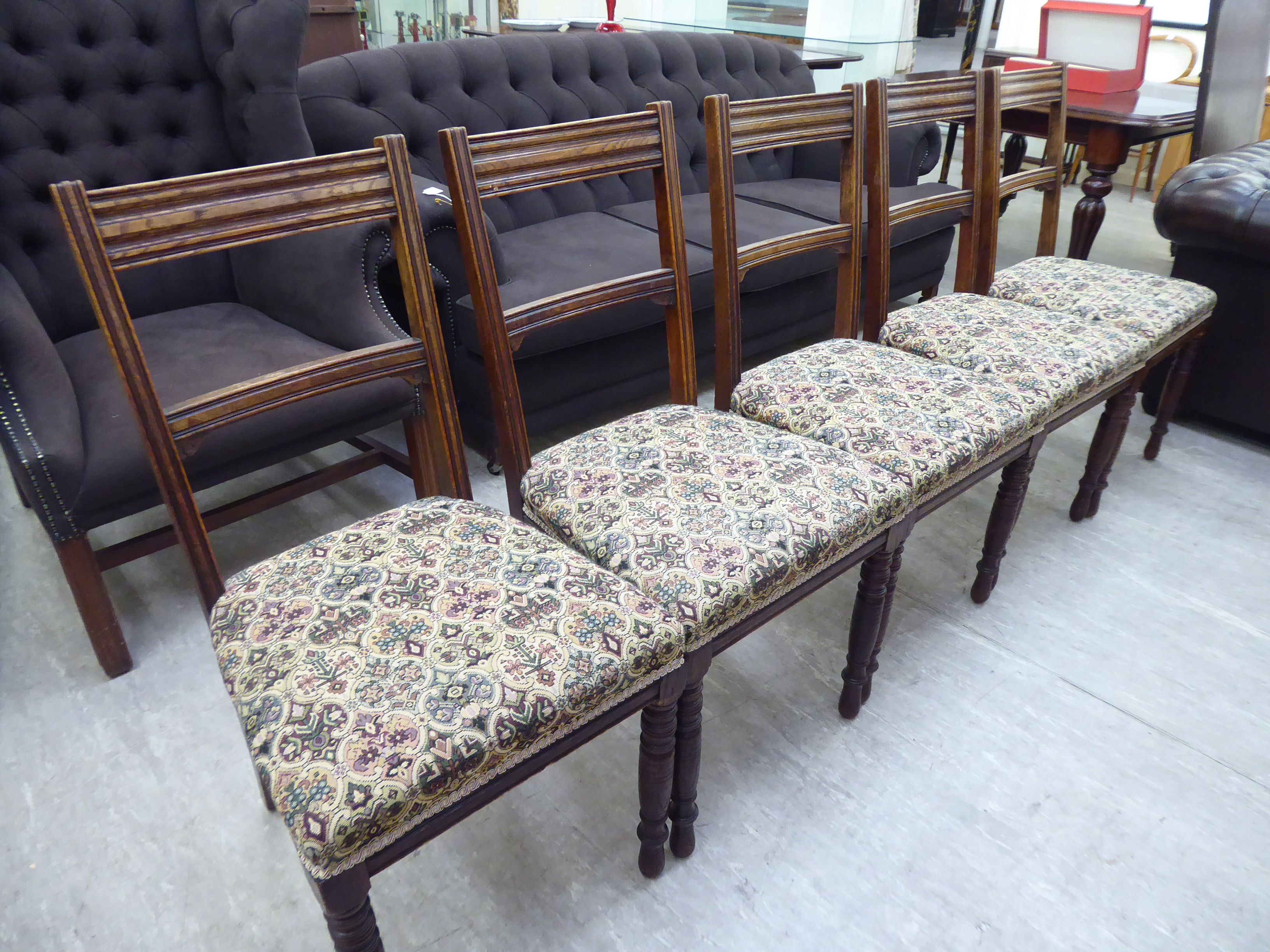 A set of five early 20thC stained oak framed bar back dining chairs with stylised patterned fabric