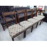 A set of five early 20thC stained oak framed bar back dining chairs with stylised patterned fabric