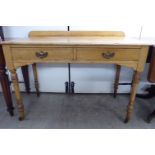 An Edwardian Arts & Crafts inspired oak two drawer desk, raised on turned,
